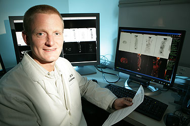 Smiling CT technologist reviewing scan